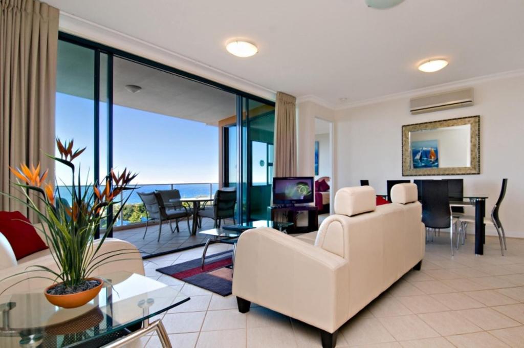 a living room with white furniture and a view of the ocean at Santorini Twin Waters in Mudjimba