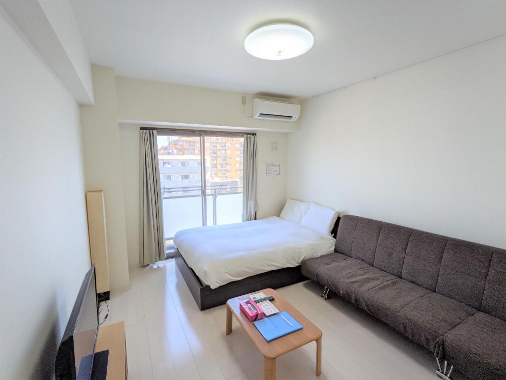 uma sala de estar com um sofá e uma cama em CIEL BLEU em Tóquio