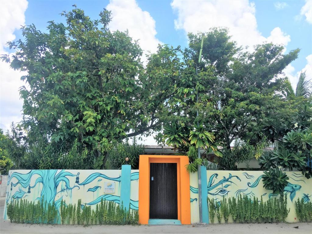 a door in a fence with a wall with graffiti at Midsummer Thulusdhoo in Thulusdhoo