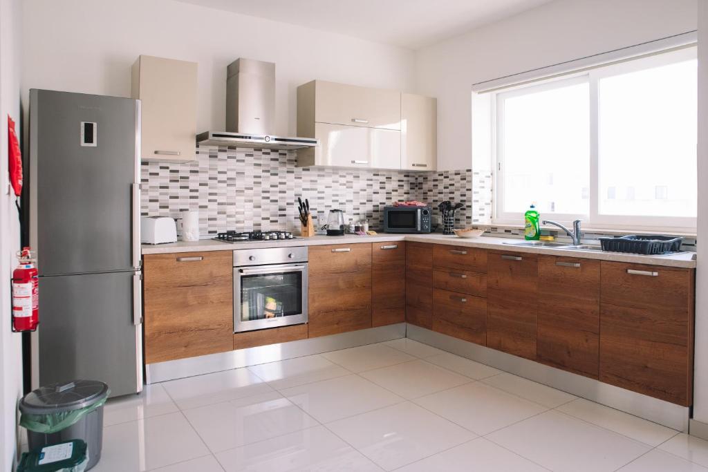 a kitchen with wooden cabinets and a stainless steel refrigerator at Modern 3 bedroom with AC apartment in Żabbar