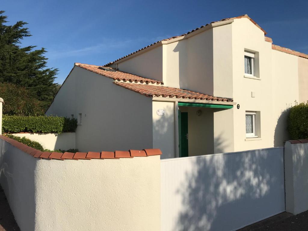 una casa blanca detrás de una valla en À 150m de la plage, en La Bétaudière