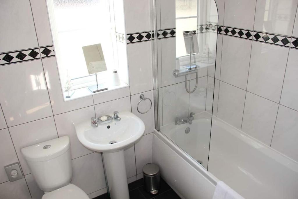 a white bathroom with a sink and a toilet and a tub at 5 Porth Gwel in Falmouth