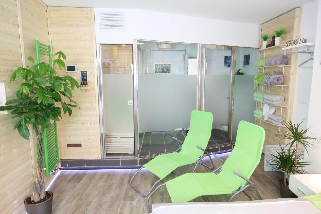 a room with two green chairs and a shower at Wellnessapartment in Oberhausen