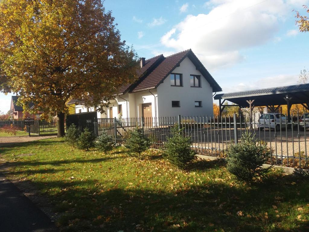 a house with a fence and trees in the yard at Noclegi Pod Dębem in Skawina