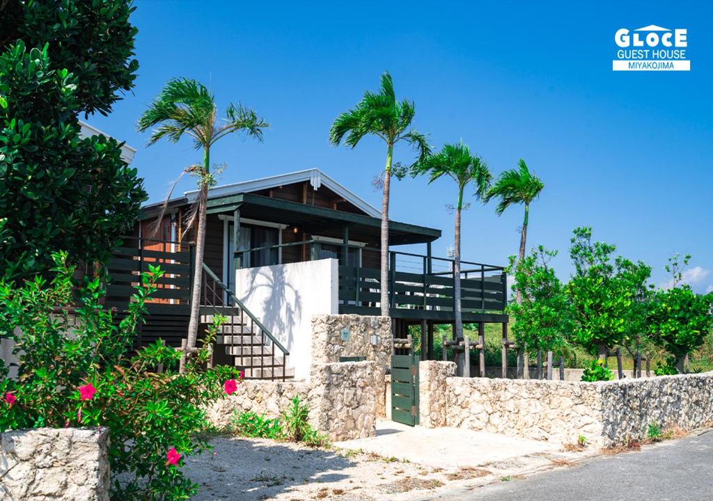a house on the beach with palm trees at 石田ヴィレッジ 満天の星空が見えるログハウスを貸し切り 宮古空港から8分 無料駐車場付 長期滞在可 in Miyako Island