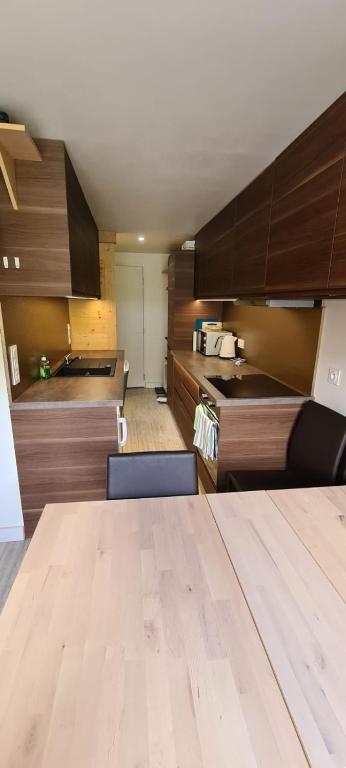 une cuisine avec des armoires en bois et une table en bois dans l'établissement Centre Station: Altineige Cosy Appart pour 4, à Val Thorens