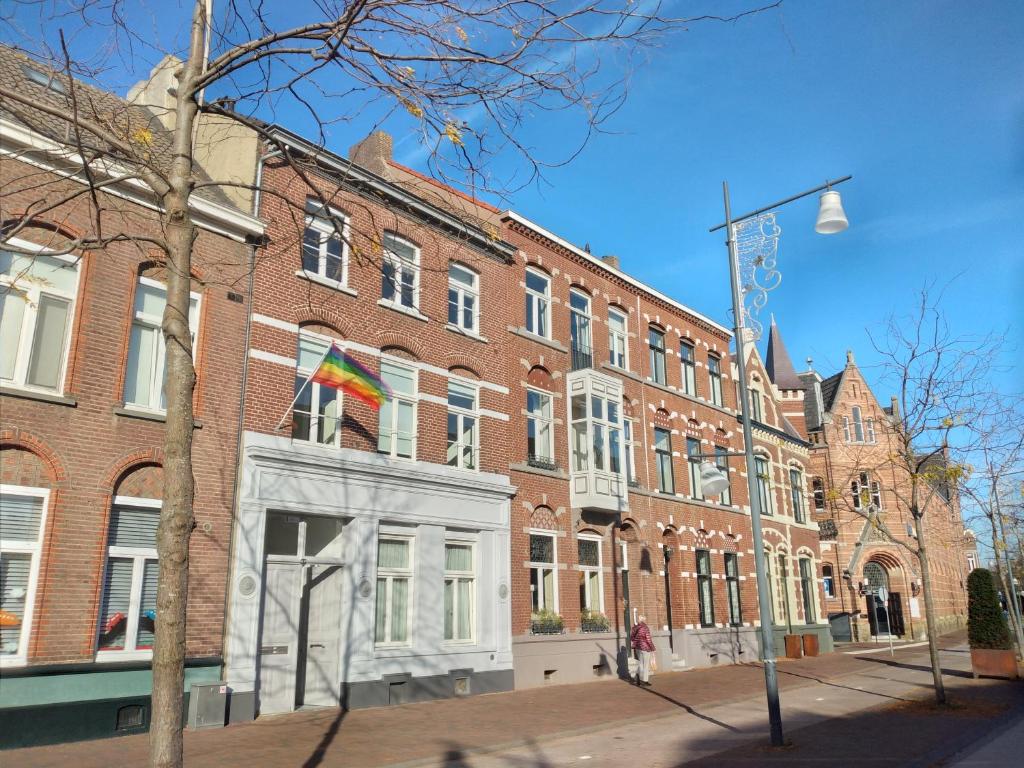 een groot bakstenen gebouw met een regenboog vlag ervoor bij Stadswoning Roermond in Roermond