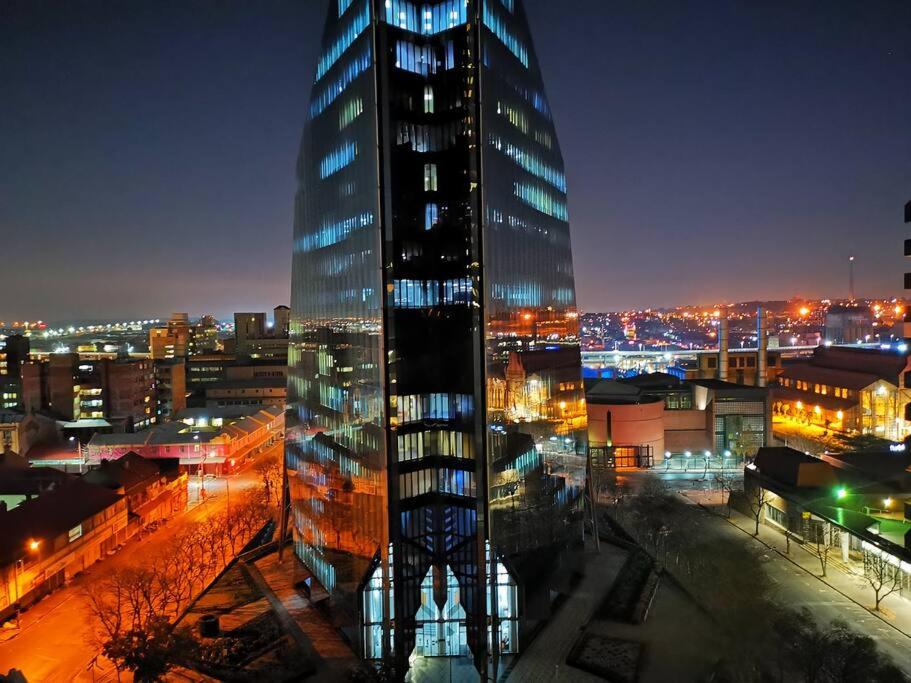 a tall glass building in a city at night at 1007-Stunning Studio apt with incredible Joburg views in Johannesburg