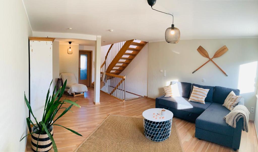 a living room with a blue couch and a staircase at Haus am See in Muhr amSee