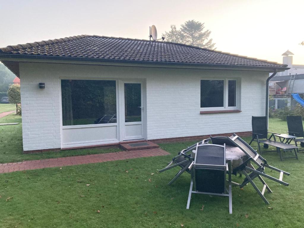 a house with chairs and a table in the yard at Bungalow 1 in Wyk auf Föhr