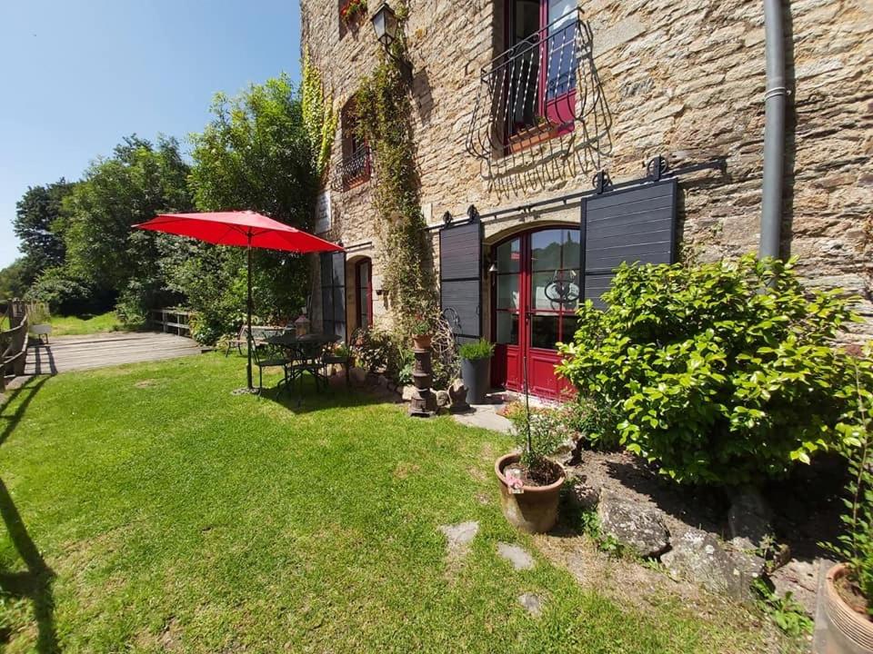 un parapluie rouge dans une cour à côté d'un bâtiment dans l'établissement le gîte Excalibur, à Bohal