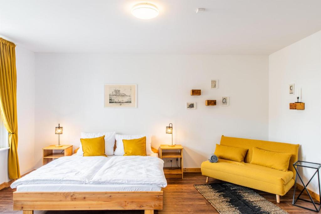 ein Schlafzimmer mit einem Bett und einem gelben Sofa in der Unterkunft Sächsischer Hof in Meißen