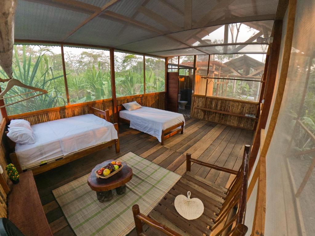 a view of a room with two beds and a table at Green House Tambopata in Puerto Maldonado