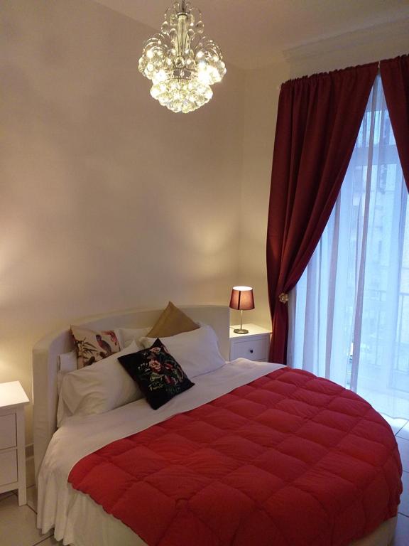 een slaapkamer met een rood bed en een kroonluchter bij B&B IL Principe in Napels
