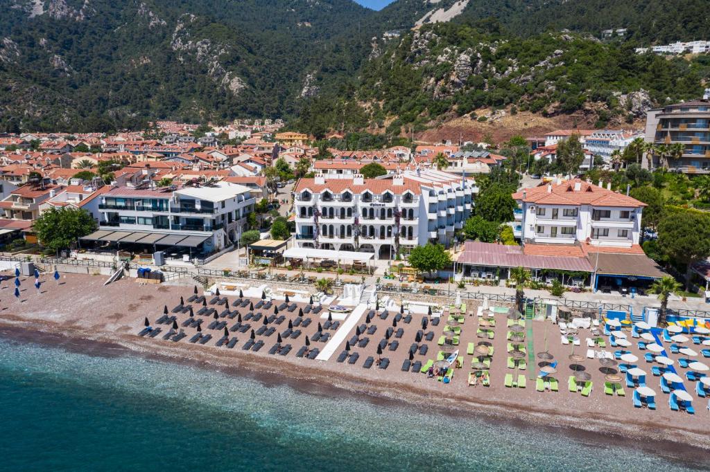 eine Luftansicht auf einen Strand mit Sonnenschirmen und Gebäuden in der Unterkunft The Diplomat Hotel in Turunç