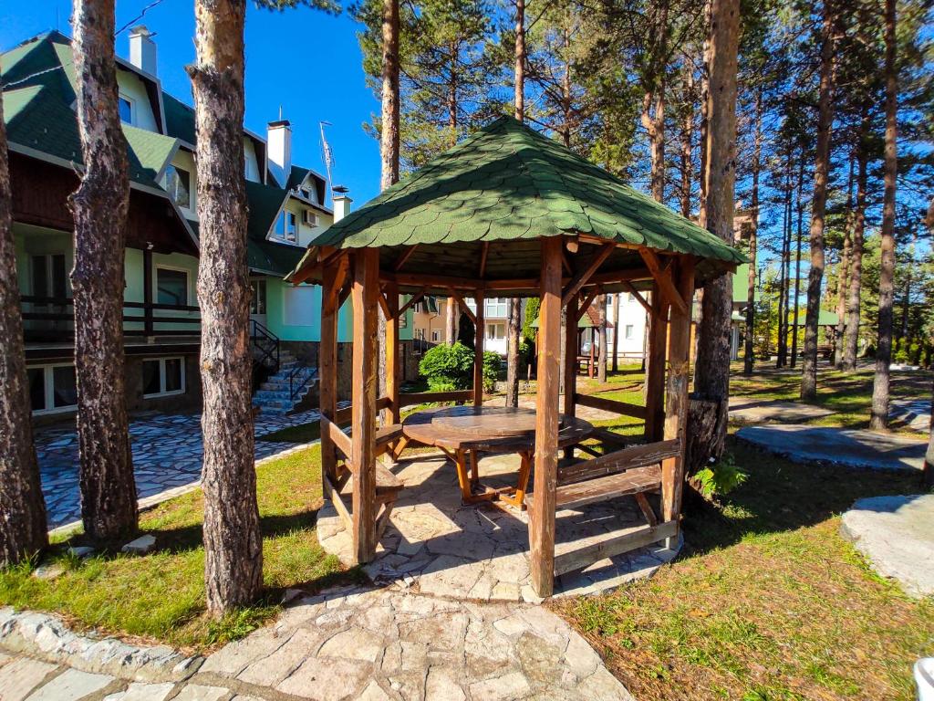 a wooden gazebo with a bench in a park at BonaMi Divcibare in Divčibare