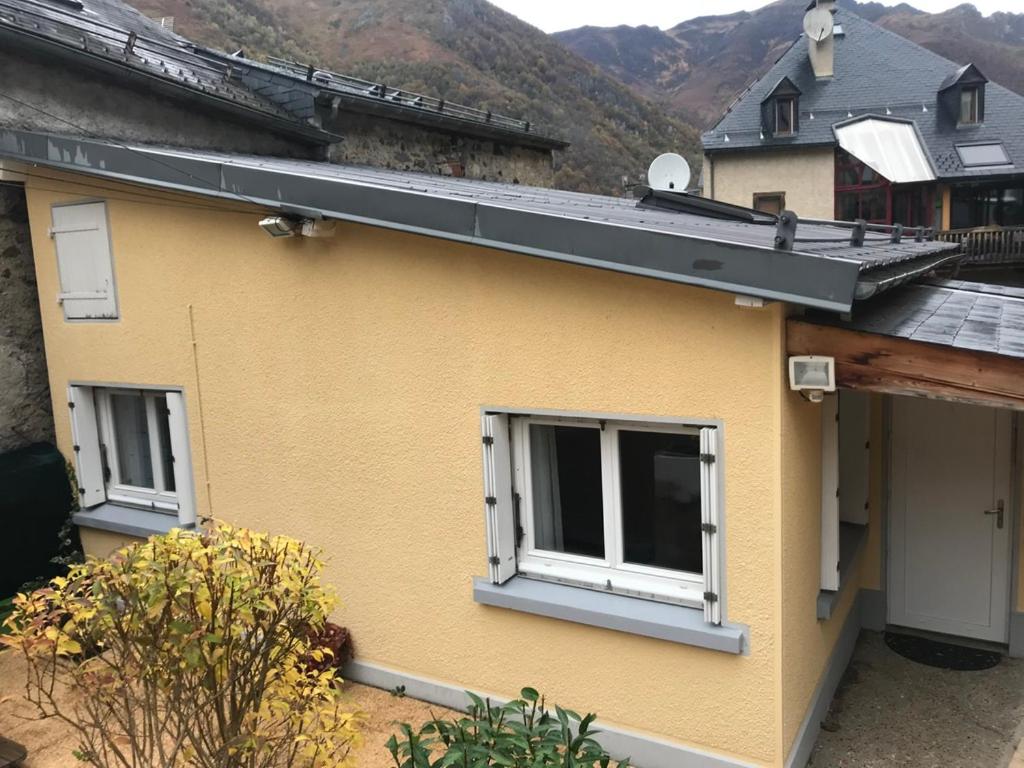 une maison jaune avec deux fenêtres et un toit dans l'établissement Petite maison proche du centre ville, à Cauterets