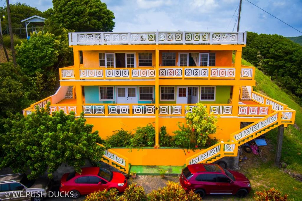 Laborie的住宿－Belle View Apartment Villa- Lilac，一座黄色的房子,前面有汽车停放