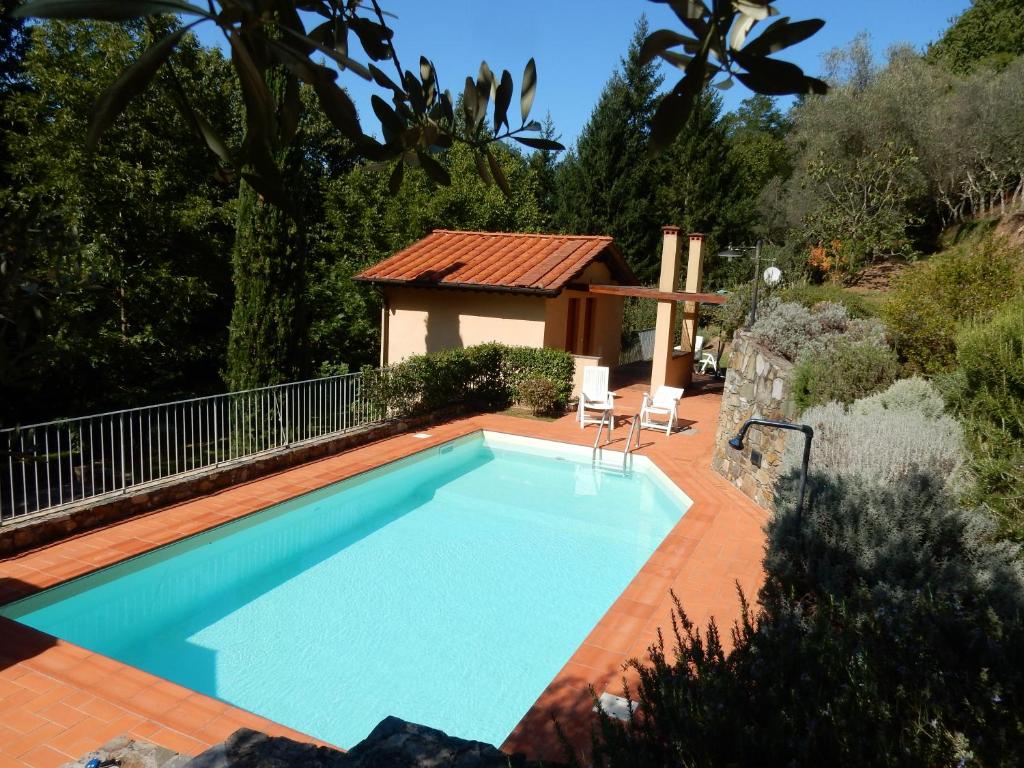 a swimming pool in a garden with a house at Oliveto Cottage in Capannori