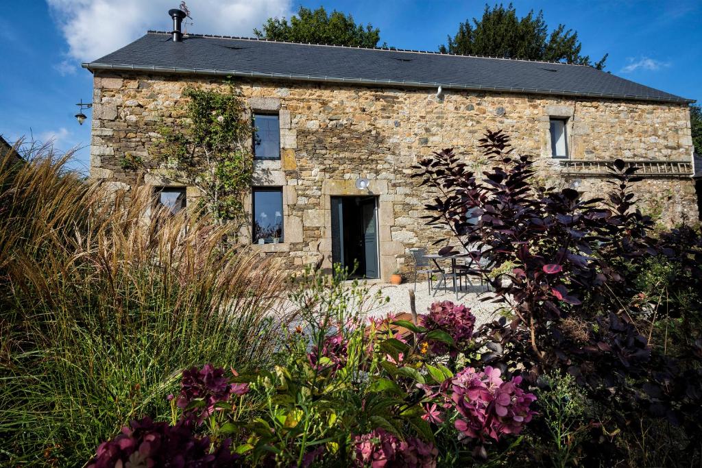 an old stone house with flowers in front of it at Au fil de l'eau in Le Vast