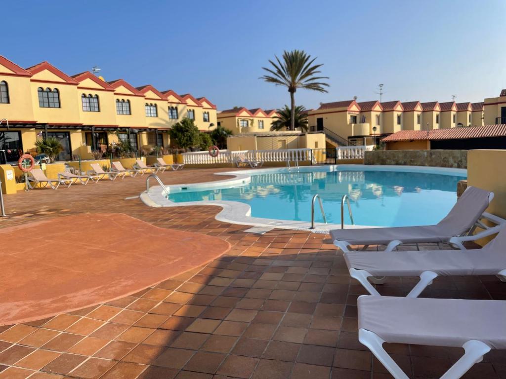 einen Pool in einem Resort mit Stühlen und Eigentumswohnungen in der Unterkunft Casa Ozzy in Costa Calma