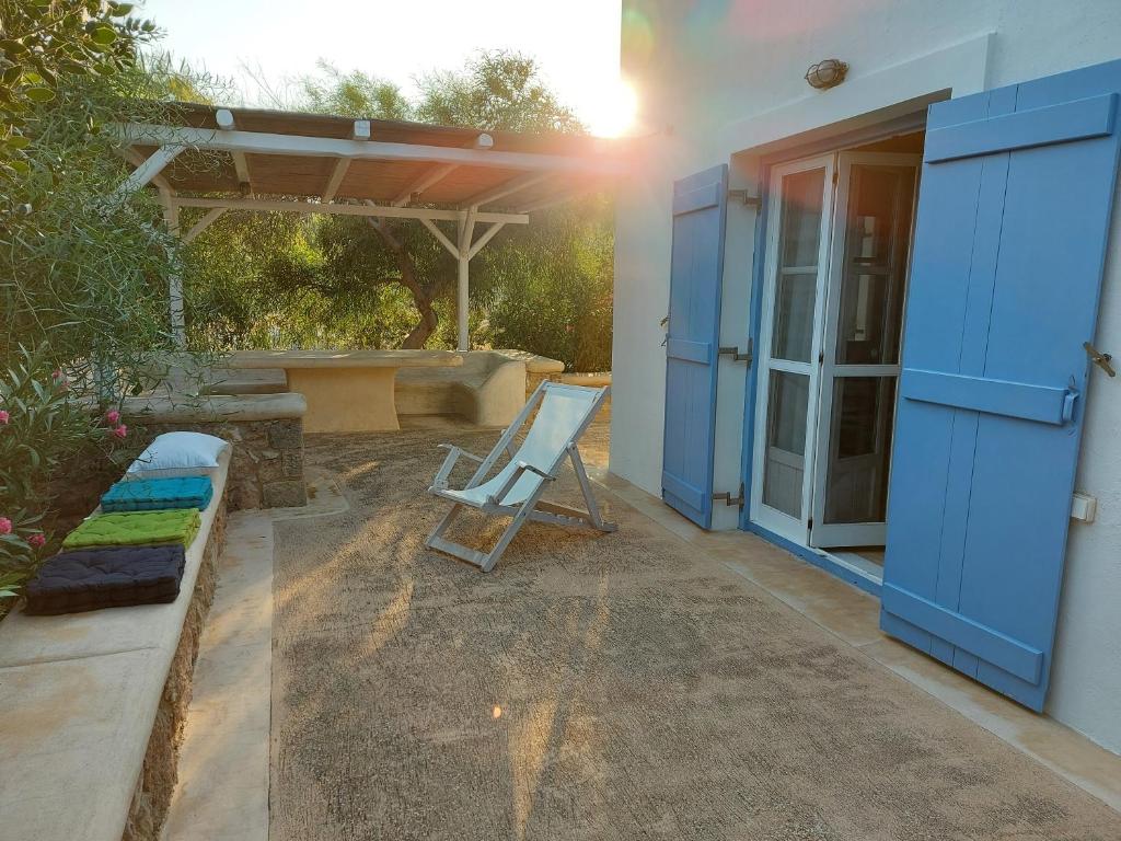 a house with a blue door and a chair on a patio at Simos suites in Elafonisos