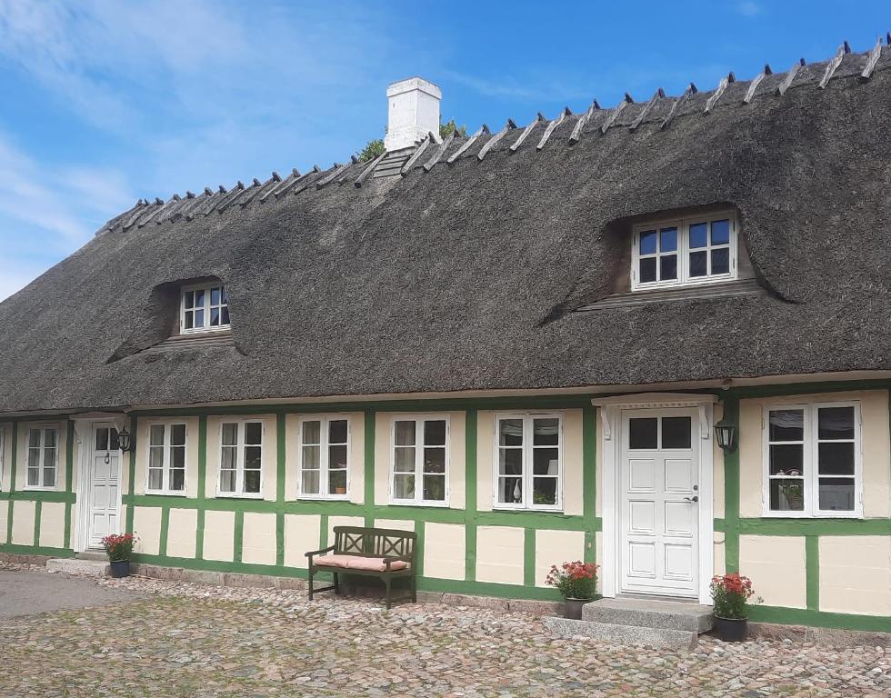 a green and white building with a roof and a bench at Staevnegaarden in Flødstrup