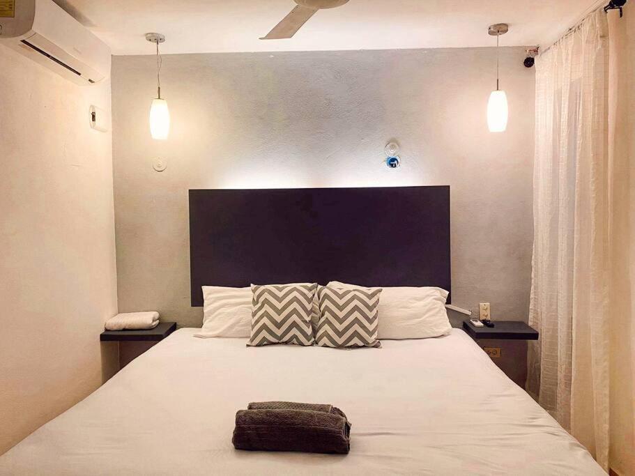 a bedroom with a large white bed with two pillows at Casa Sol Y Luna Luxury Valladolid Yucatán in Valladolid