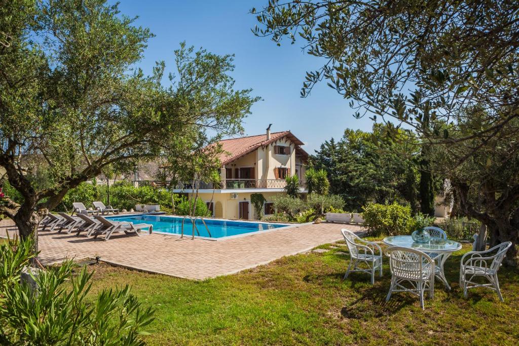 een huis met een zwembad en een tafel en stoelen bij Villa Glavina in Lixouri