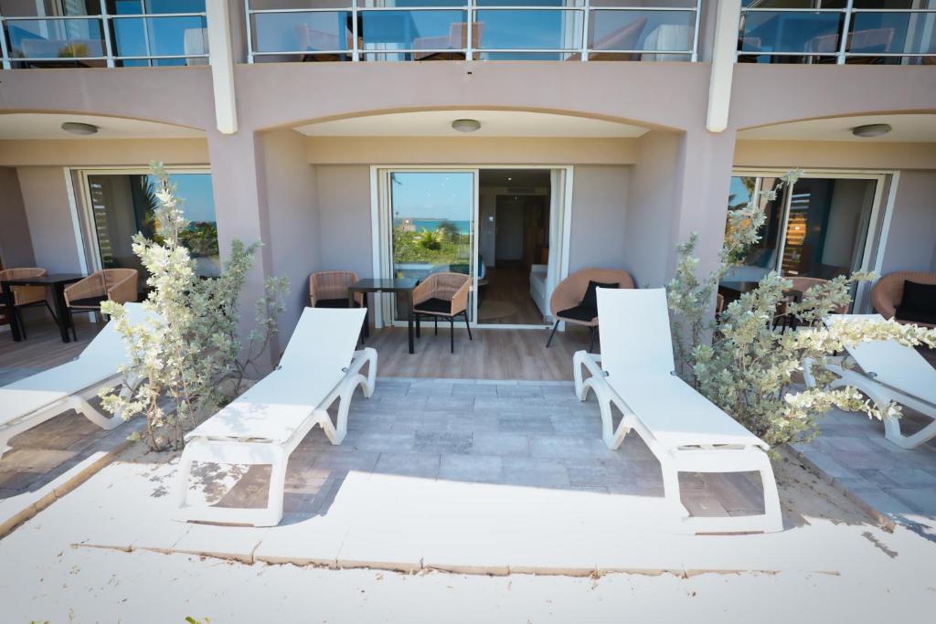 a group of white benches on a patio at Orient Beach Hotel in Orient Bay