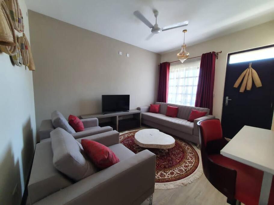 a living room with a couch and a tv at Elegant 1 Bedroom Condo Near Vipingo Ridge Golf Resort in Kilifi