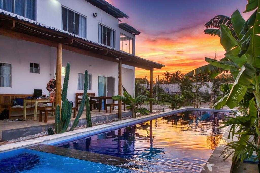 uma villa com uma piscina em frente a um pôr-do-sol em Mykonos Residence em São Miguel do Gostoso