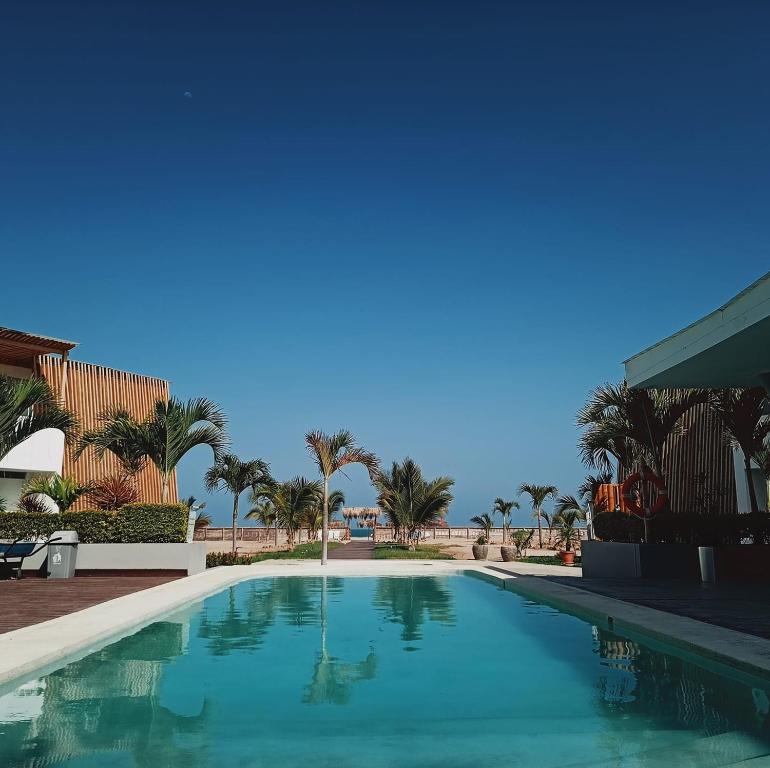 a swimming pool with palm trees in the background at Deplaya Zorritos-Tumbes in Bocapán