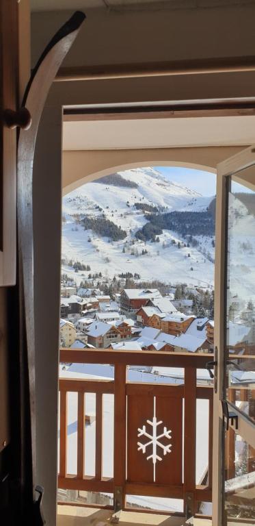 a view of a snowy town through an open door at Studio Alpheratz Forest - 1 à 3 pers - WIFI, balcon, vue piste et glacier Muzelle, calme, proche commerces et pistes- TSC Super Venosc à 80m in Les Deux Alpes