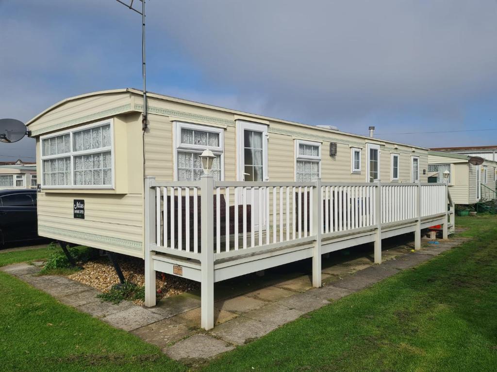 uma casa amarela com uma cerca branca num quintal em 6 Berth on Seaview (Fanfare) em Ingoldmells