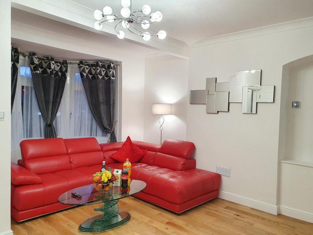 a living room with a red couch and a glass table at Glasgow Comfortable and Modern 3 Bedroom Mid Terraced Villa in Glasgow