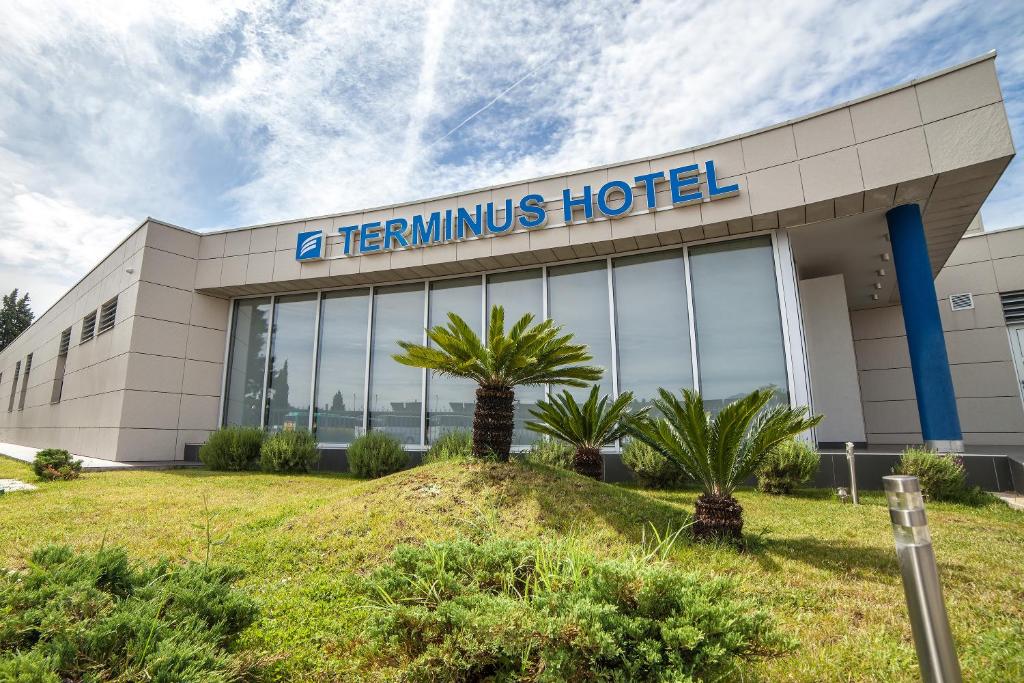 een thermills hotelgebouw met palmbomen aan de voorkant bij Hotel Terminus in Podgorica