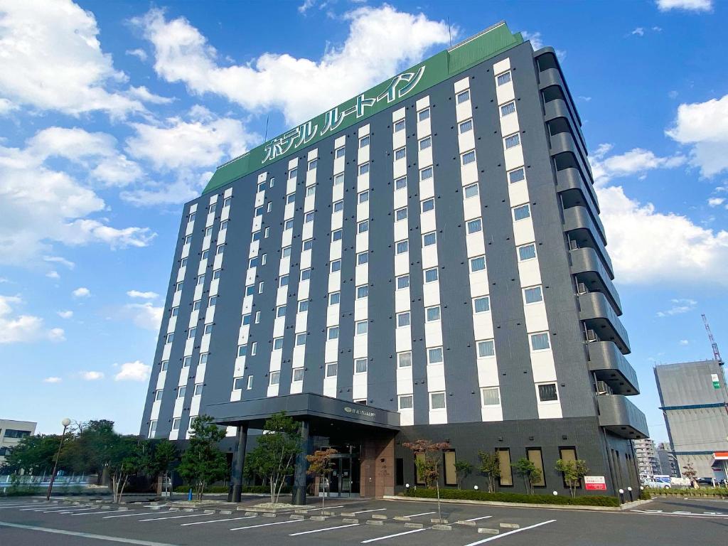 a large building with a sign on top of it at Hotel Route-inn Natori in Natori