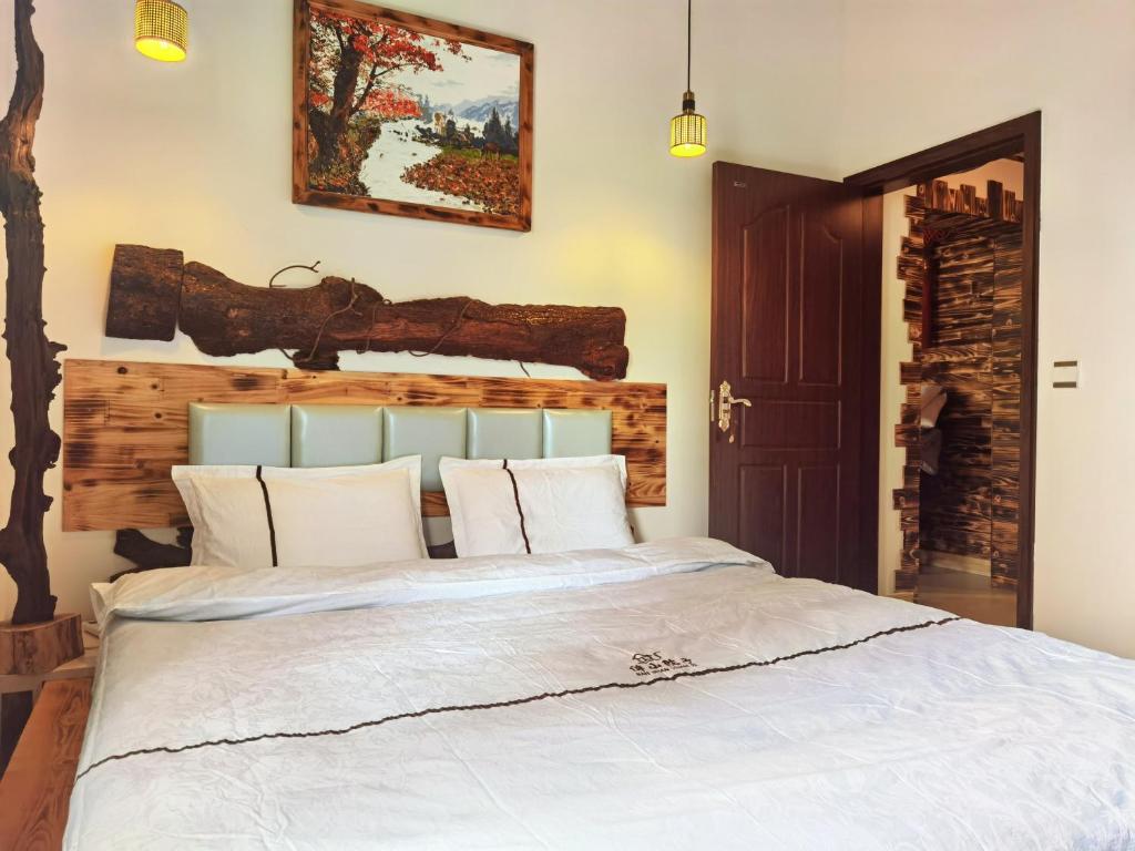 una camera da letto con un letto bianco con testiera in legno di Banshan Yard a Ya'an