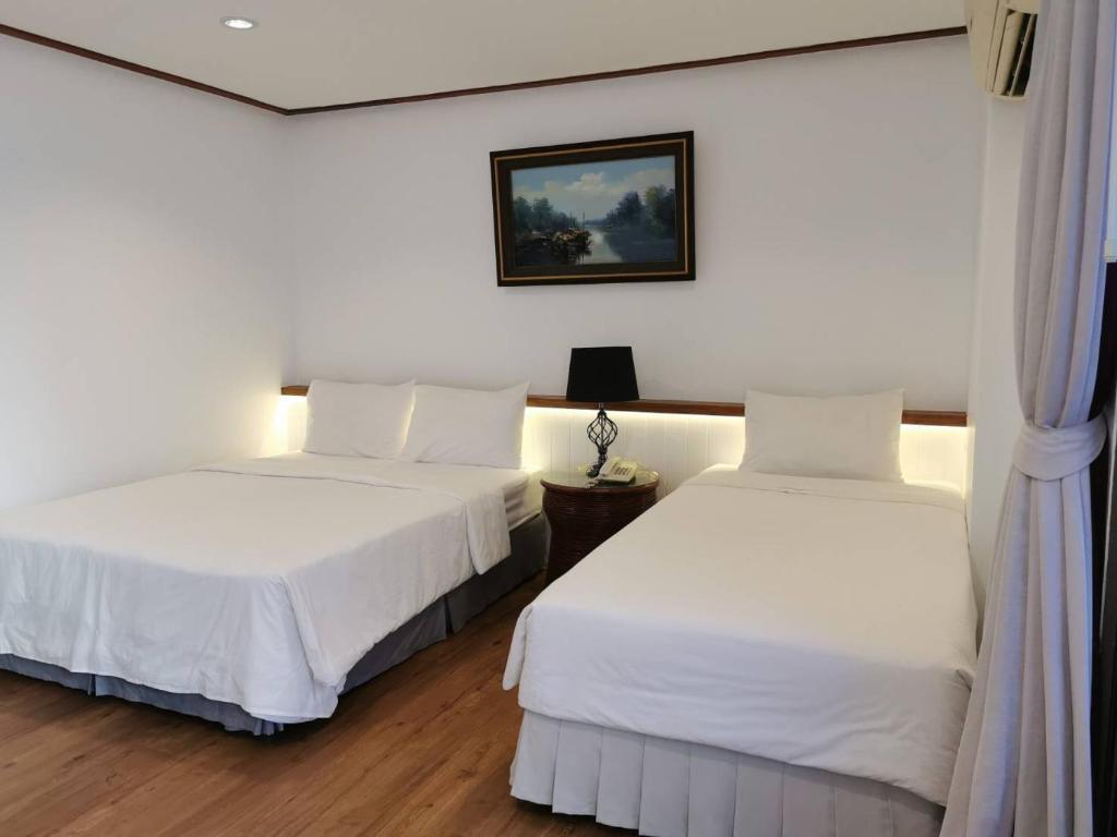 twee bedden in een kamer met witte muren en houten vloeren bij BaanBusarin Hotel in Hua Hin