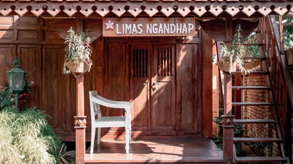 a white chair sitting in front of a wooden door at Cokro Hinggil - Traditional View in Sleman