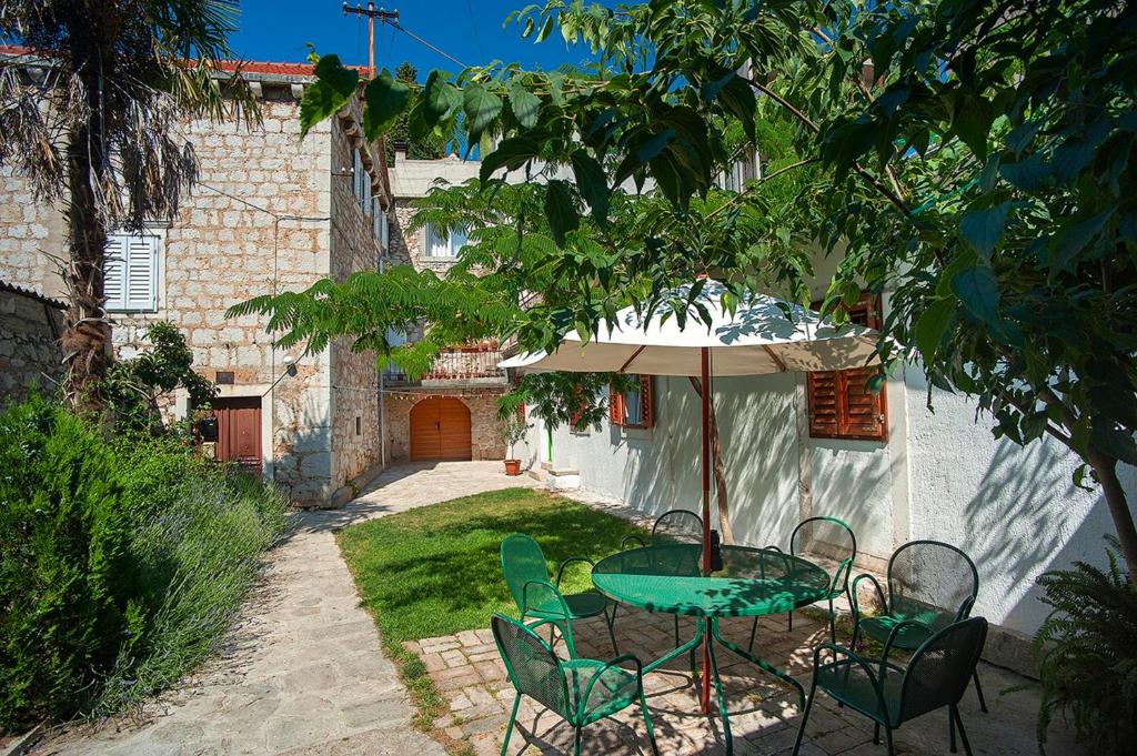 uma mesa e cadeiras com um guarda-sol num quintal em Dalmatian Garden - FREE parking - city centre em Sibenik