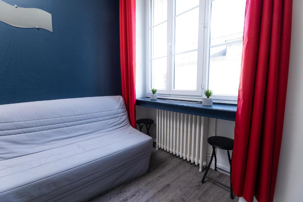 a bedroom with a bed with red curtains and a window at Au nid douillet - Dormir Comme A La Maison in Châteaubriant