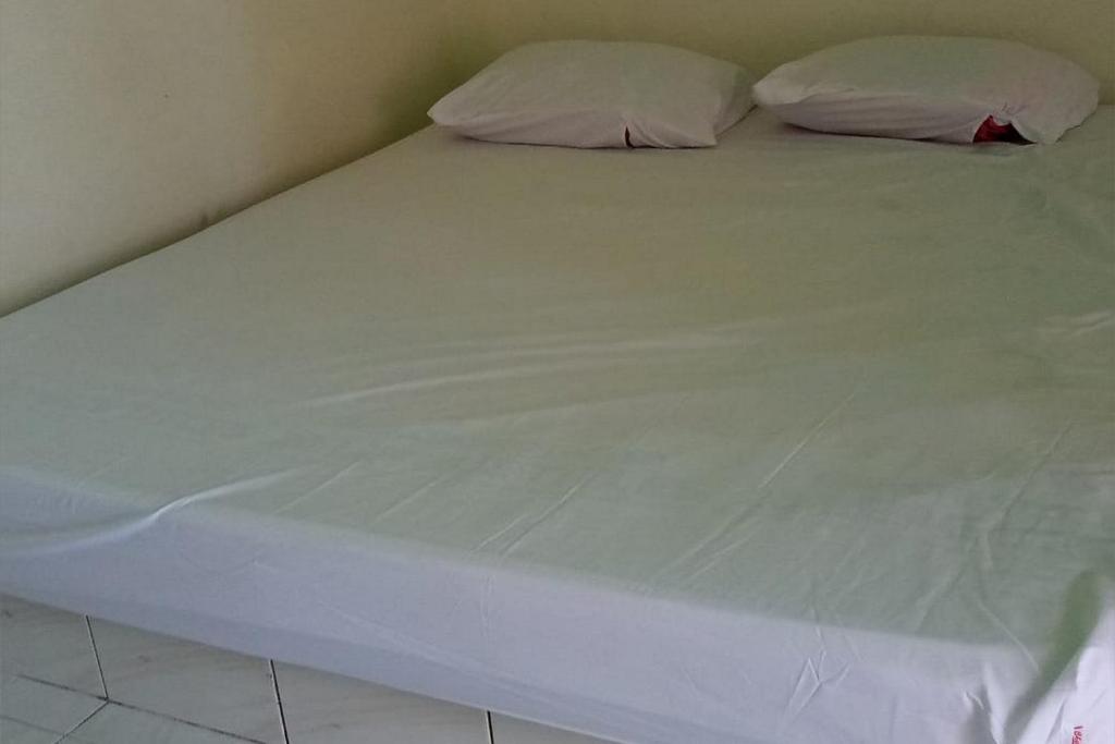 een groot wit bed met 2 kussens erop bij KoolKost Syariah near Living Plaza Purwokerto (minimum stay 6 nights) in Purwokerto