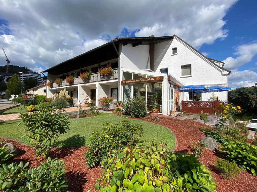 una casa blanca con un jardín delante de ella en Café & Pension Meine Sonne ... Sole Mio, en Bad Sooden-Allendorf