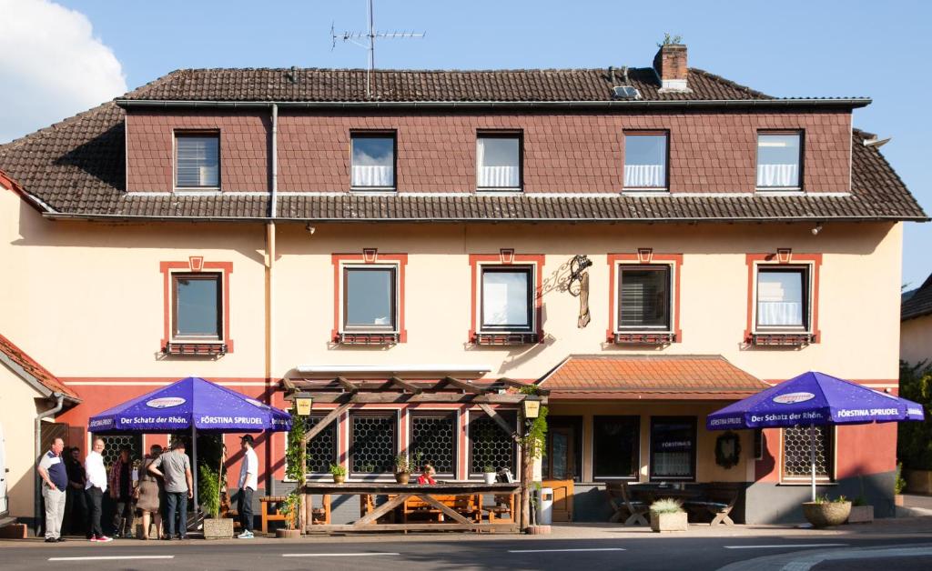 ein Gebäude mit blauen Sonnenschirmen davor in der Unterkunft Herzog's Ulsterbrücke in Tann