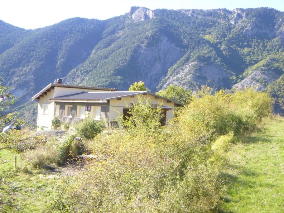 a house on a hill with mountains in the background at La Miellerie des Nuages in Prads-Haute-Bléone