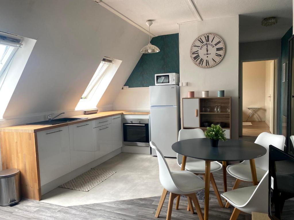 a kitchen with a table and a clock on the wall at Cocon sous les toits - vue sur les châteaux et le vignoble - proche centre ville - parking gratuit in Sélestat