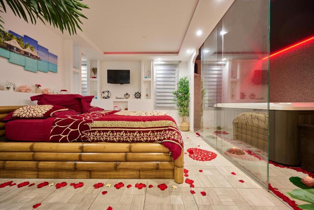 a bedroom with a bed with red sheets and red roses on the floor at Sablotin SPA in Toulouse