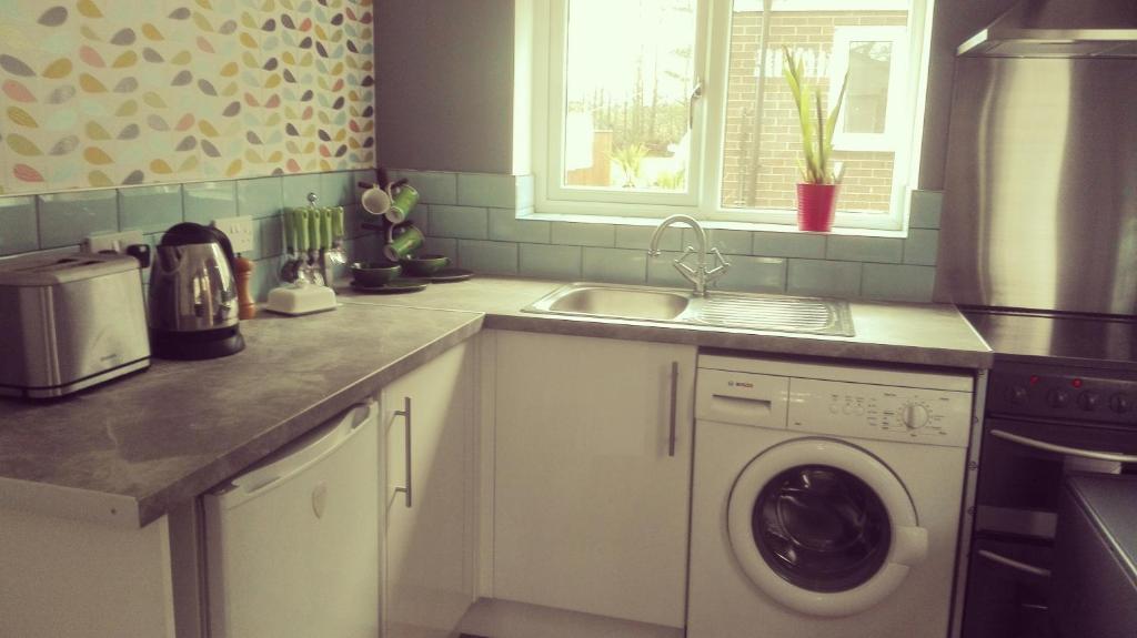 a kitchen with a sink and a washing machine at Garden Apartment Morpeth- with lockable bike storage! in Morpeth